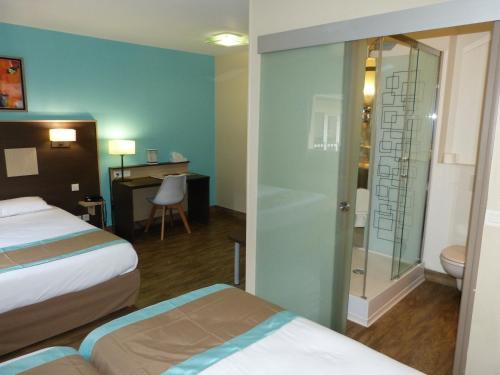 a hotel room with two beds and a desk at Hotel ARBOR - Les Hunaudieres - Le Mans Sud - Mulsanne in Mulsanne