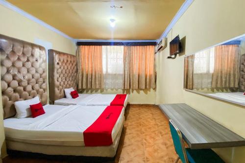 a bedroom with two beds and a bench in it at RedDoorz Syariah At Hotel Matahari 1 Jambi in Jambi