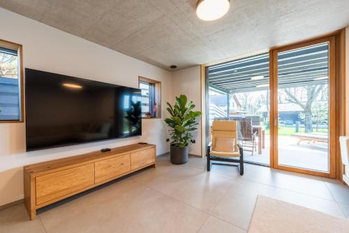 a living room with a large television and a chair at The Alpine House Otto in Begunje na Gorenjskem