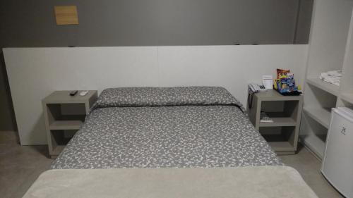 a bed in a room with two shelves at Hotel Palmas Executivo in Balneário Camboriú