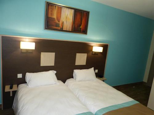 two beds in a room with two white pillows at Hotel ARBOR - Les Hunaudieres - Le Mans Sud - Mulsanne in Mulsanne