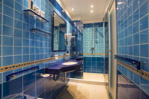 a blue tiled bathroom with a sink and a shower at Hotel Terme Saint Raphael in Barano d'Ischia