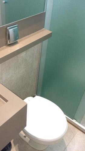 a white toilet in a bathroom with a mirror at Hotel Palmas Executivo in Balneário Camboriú