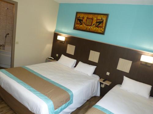 a hotel room with two beds and a picture on the wall at Hotel ARBOR - Les Hunaudieres - Le Mans Sud - Mulsanne in Mulsanne