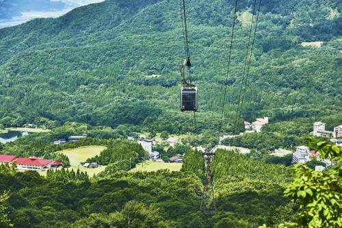 a gondola flying over a village in the mountains at YuiLocalZao in Zaō Onsen