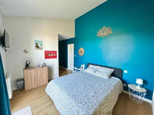 a bedroom with a bed and a blue wall at Logis des vignes in Saint-Émilion