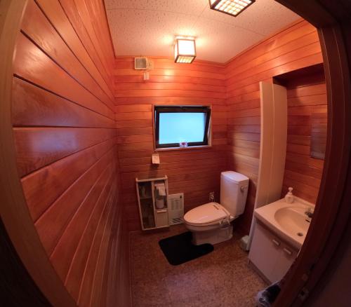 a bathroom with wooden walls and a toilet and a sink at Tsumugu dom in Ueda