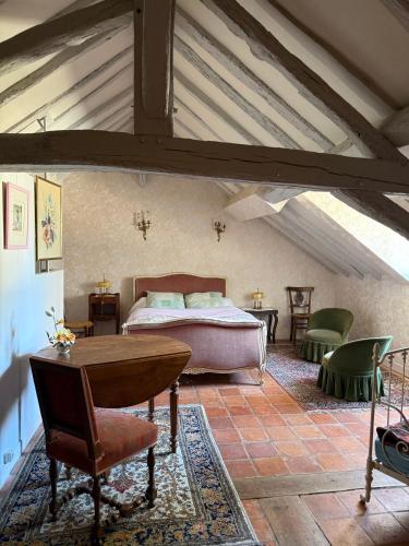a bedroom with a bed and a table and chairs at Lorcival in Savennières