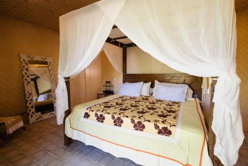 a bedroom with a bed with a canopy at Fare Teiti Beach Bungalow in Haapiti