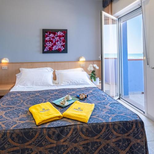 a bed with two towels and a tray of food on it at Hotel Marina in Fano