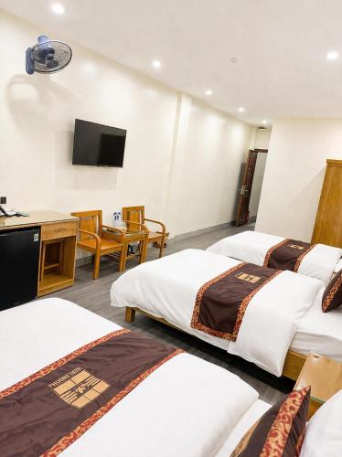 a hotel room with three beds and a television at Hoa Cương Hotel 2- Hà Giang in Ha Giang