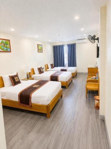a hotel room with three beds and a chair at Hoa Cương Hotel 2- Hà Giang in Ha Giang