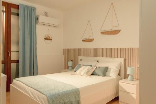 a bedroom with a white bed with two sails on the wall at SHARED SWIMMING POOL, House relax Lu Bagnu in Castelsardo