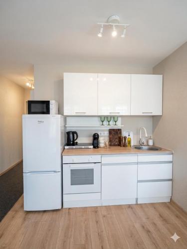 a kitchen with white cabinets and a white refrigerator at Naomi apartaments in Saldus