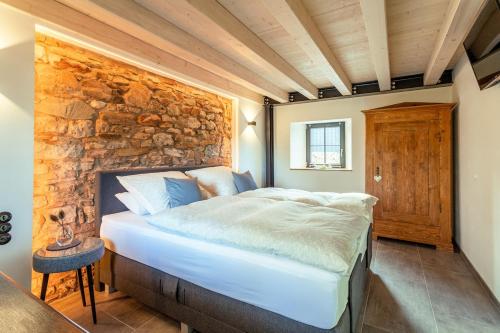 a bed in a room with a stone wall at Glamorous Cottage mit Kamin und Sauna in Dahlem