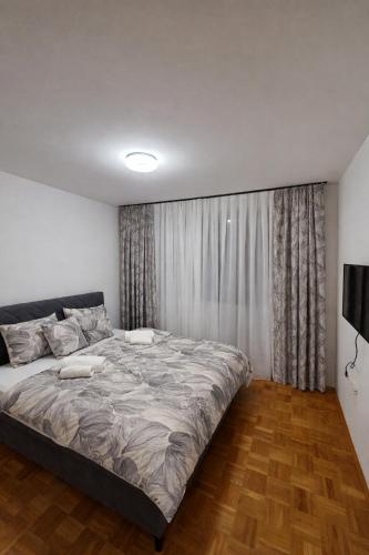 a bedroom with a large bed in front of a window at Apartman Anja'K in Doboj