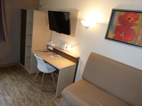 a hotel room with a desk with a television and a bed at Hotel ARBOR - Les Hunaudieres - Le Mans Sud - Mulsanne in Mulsanne