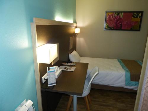 a hotel room with a bed and a desk with a desk at Hotel ARBOR - Les Hunaudieres - Le Mans Sud - Mulsanne in Mulsanne
