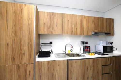 a kitchen with wooden cabinets and a sink at Central Stay Studio Apartment near Cleveland and Abu Dhabi Mall in Abu Dhabi