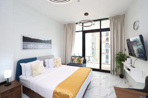 a white bedroom with a large bed and a tv at Central Stay Studio Apartment near Cleveland and Abu Dhabi Mall in Abu Dhabi