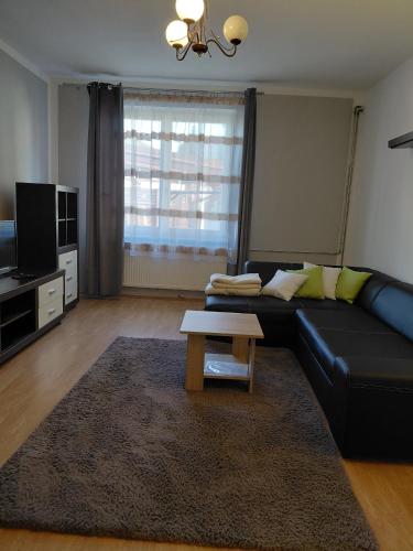 a living room with a black couch and a coffee table at Apartman Kováčová in Kováčová