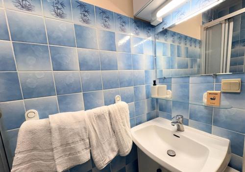 a blue tiled bathroom with a sink and a mirror at Studio Cosy Carnot in Compiègne