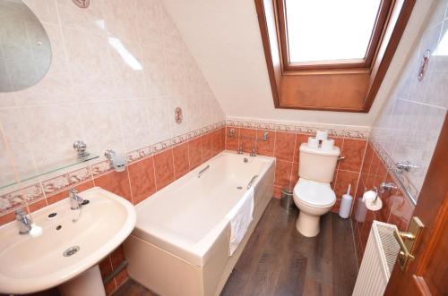 a bathroom with a tub and a toilet and a sink at Kingfisher Lodge in Wroxham