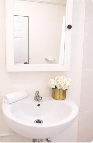 a bathroom sink with a mirror and flowers on it at PINK POUI Spaces Vacation Rentals in Arima