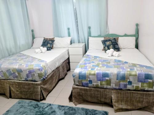 two beds sitting next to each other in a room at Summer Breeze Villa in Lucea