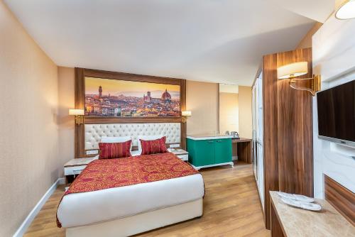 a hotel room with a bed and a flat screen tv at Litore Resort Hotel & Spa - Ultra All Inclusive in Okurcalar