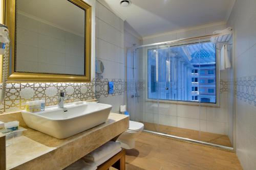 a bathroom with a sink and a toilet and a mirror at Litore Resort Hotel & Spa - Ultra All Inclusive in Okurcalar