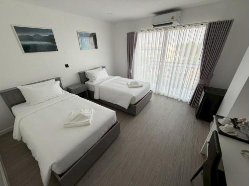 a hotel room with two beds and a television at The View Hotel โรงแรมเดอะวิว นครศรีธรรมราช in Nakhon Si Thammarat
