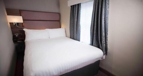 a bed in a hotel room with a window at Best Western Chilworth Manor Hotel in Southampton
