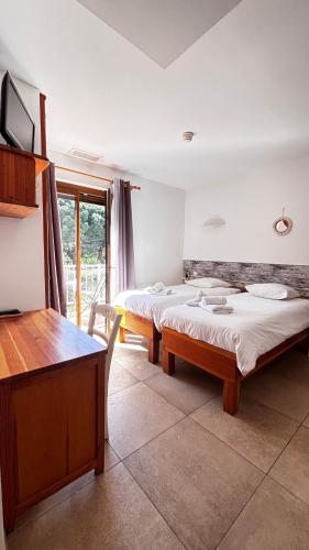 two beds in a room with a table and a desk at Hotel La Bastide in Le Lavandou