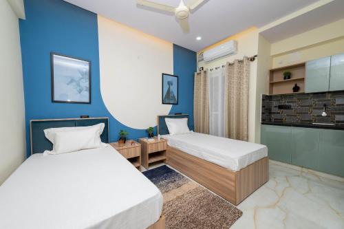 two beds in a room with blue walls at C Suites Gilbert in Bangalore