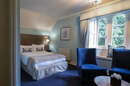 a bedroom with a bed and two blue chairs at The Parsonage Hotel & Spa in York