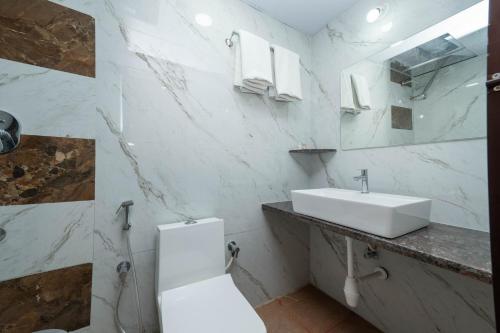 a white bathroom with a sink and a toilet at C Suites Gilbert in Bangalore
