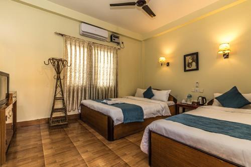 a hotel room with two beds and a television at Hotel Aahar chitawan in Bharatpur