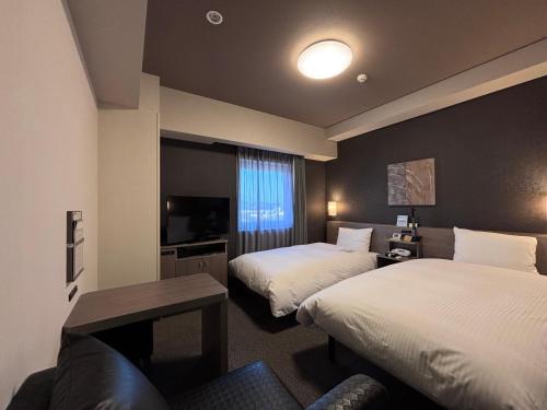 a hotel room with two beds and a television at Hotel Route-Inn Masuda in Masuda
