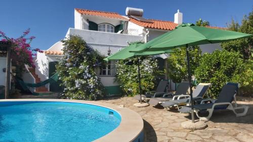 a pool with chairs and an umbrella next to a house at Casa Delfim - Casas Azul&Verde in Alte