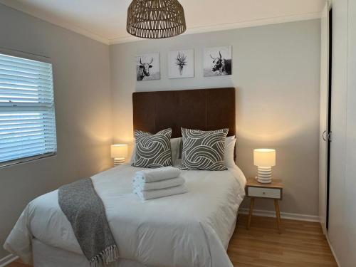 a bedroom with a large white bed with two lamps at The Little Cove in Strand