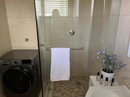 a bathroom with a shower with a washing machine at The Little Cove in Strand
