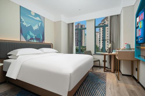 a bedroom with a large white bed and a desk at Echarm Hotel Guangzhou East Railway Station South China Normal University Metro Station in Guangzhou