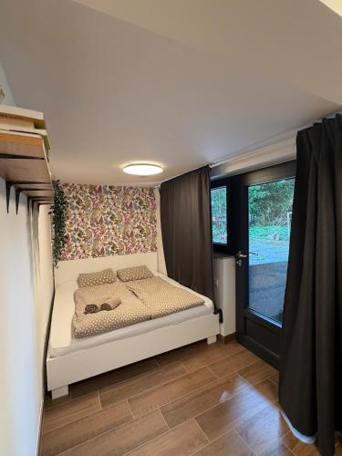 a small bedroom with a bed in a room with a window at Blossoming Hidden Nest with Garden in Ljubljana