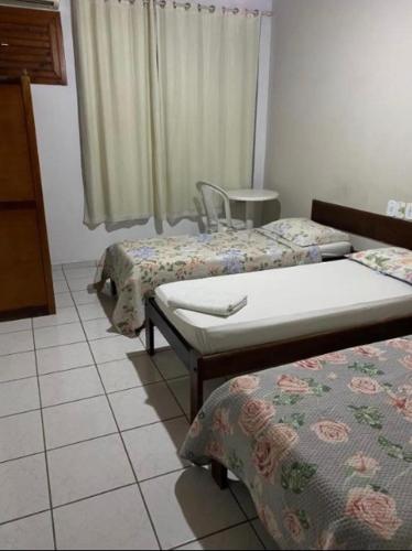 ein Zimmer mit zwei Betten und einem Stuhl in der Unterkunft Hotel Malacarne in Teixeira de Freitas