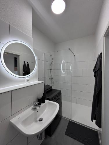 ein weißes Badezimmer mit Waschbecken und Spiegel in der Unterkunft Apartment 45 - Moderne, ruhige 2 Zimmer-Wohnung mit WLAN in Wittenberge, Komplett ausgestattet mit EBK, ideal für Business, Privataufenthalte, Radfahrer sowie kurze und längere Aufenthalte - einzeln oder als Paar - Nahe Bahnhof, Zentrum - Fahrradgarage in Wittenberge