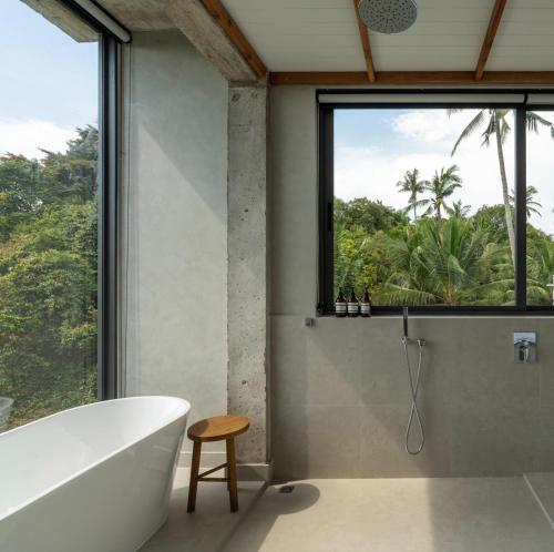 a bathroom with a tub and a large window at Palm Stone Villa in Haad Pleayleam
