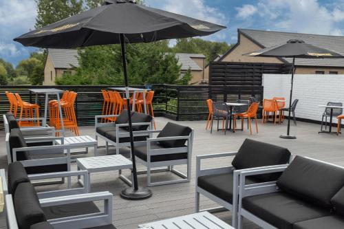 a patio with chairs and tables and an umbrella at Cambridge Bar Hill Hotel, BW Signature Collection in Cambridge