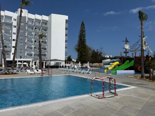 a swimming pool with a slide in front of a building at Papouis Protaras Hotel in Protaras