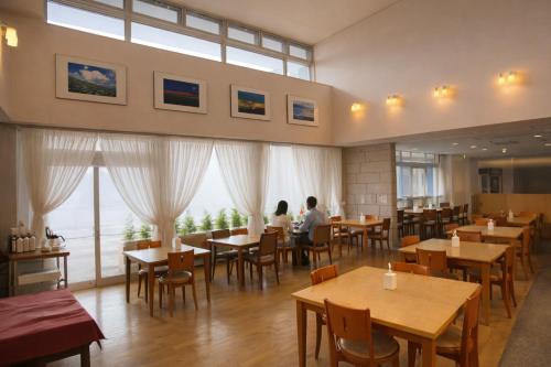 two people sitting at tables in a restaurant at Hotel Lavenir in Biei